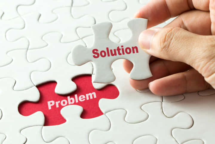 Hand putting last piece of puzzle with the word solution to fix the problem