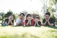 Une famille de cinq personnes, allongée sur la pelouse et souriant joyeusement, pendant leur séjour au Japon.
