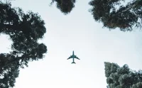 An airplane is flying over the forest.