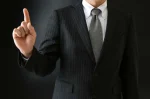 指を上に指しているスーツ姿の男性