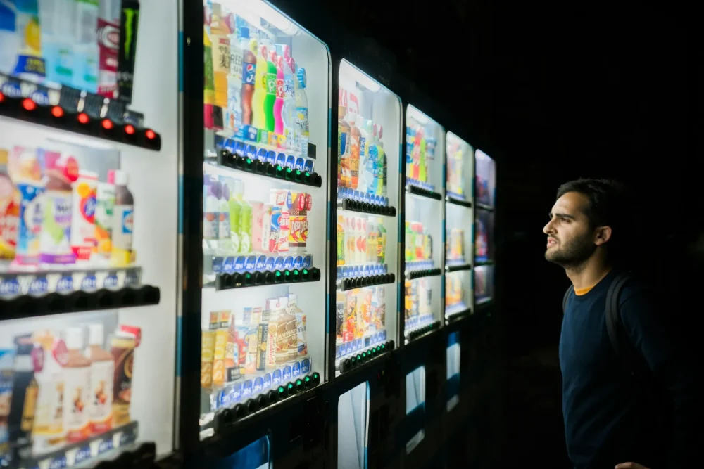 A foreign man is puzzled because he doesn't know how to use a vending machine.